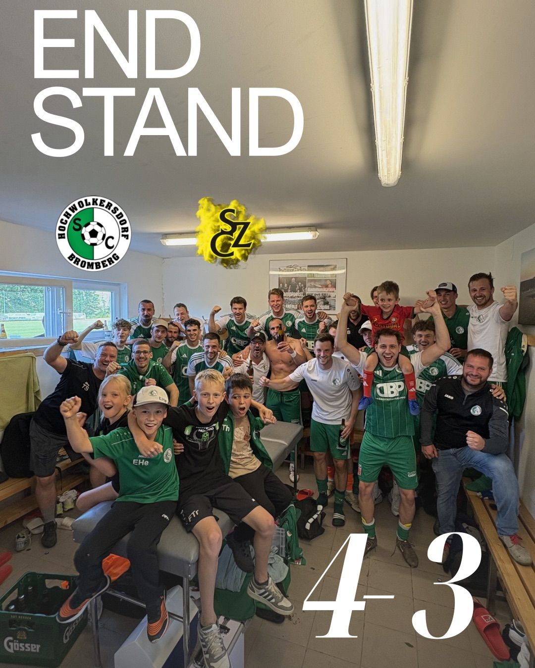 Eine Fußballmannschaft feiert einen Sieg in der Umkleidekabine. Ein Banner steht 'END STAND'. Spieler und Fans jubeln.