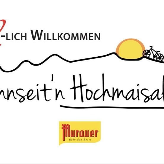 Ein Werbebild mit einer Bergsilhouette, einem untergehenden Sonnen und Fahrrädern. Der Text lautet 'Herzlich Willkommen' und 'onseit'n Hochmaisalm' mit einem Logo für 'Murauer' darunter.