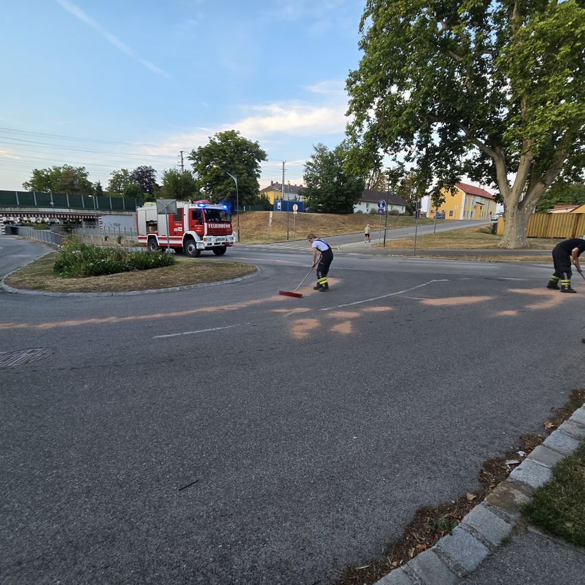 Two workers are painting road markings on a street with a fire truck parked nearby.