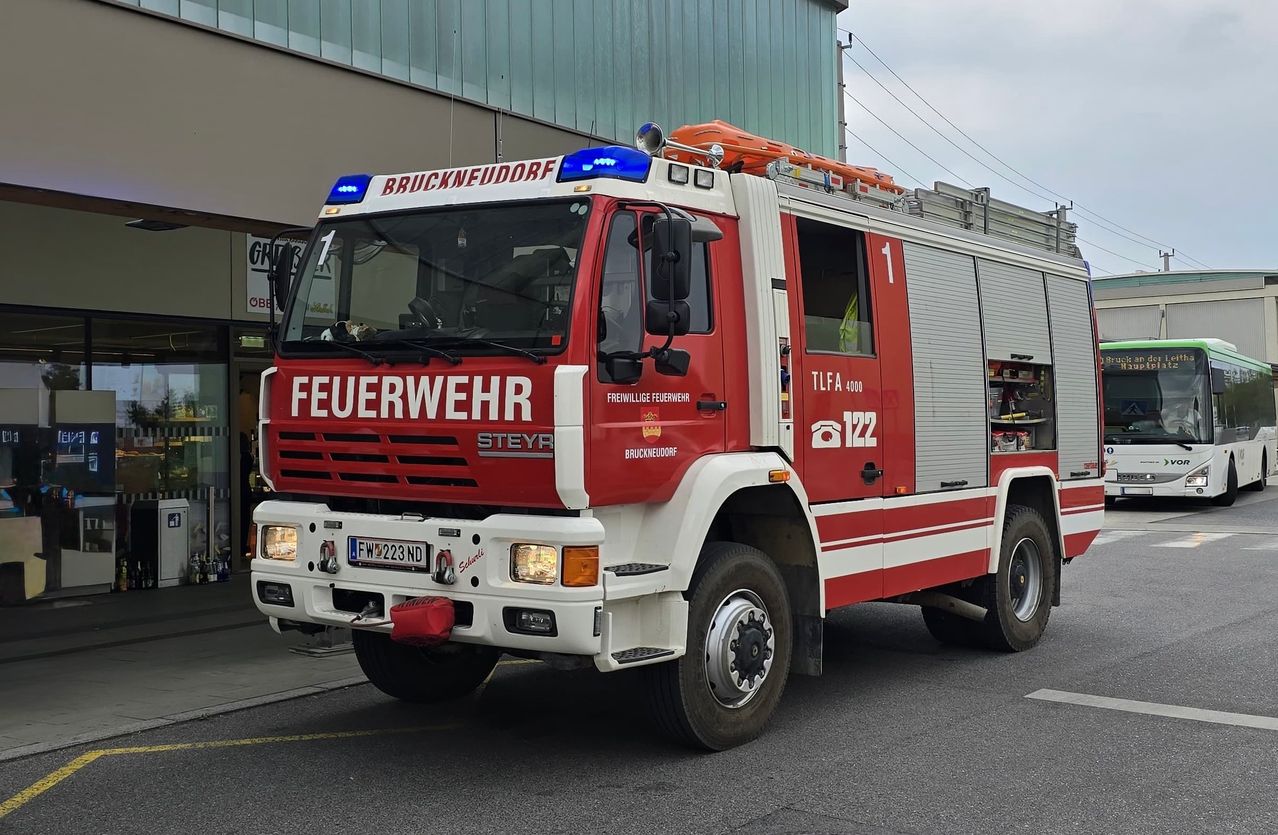 A red and white fire truck with the word 'Feuerwehr' on the front and the number '1' on the side, parked on the side of the road.