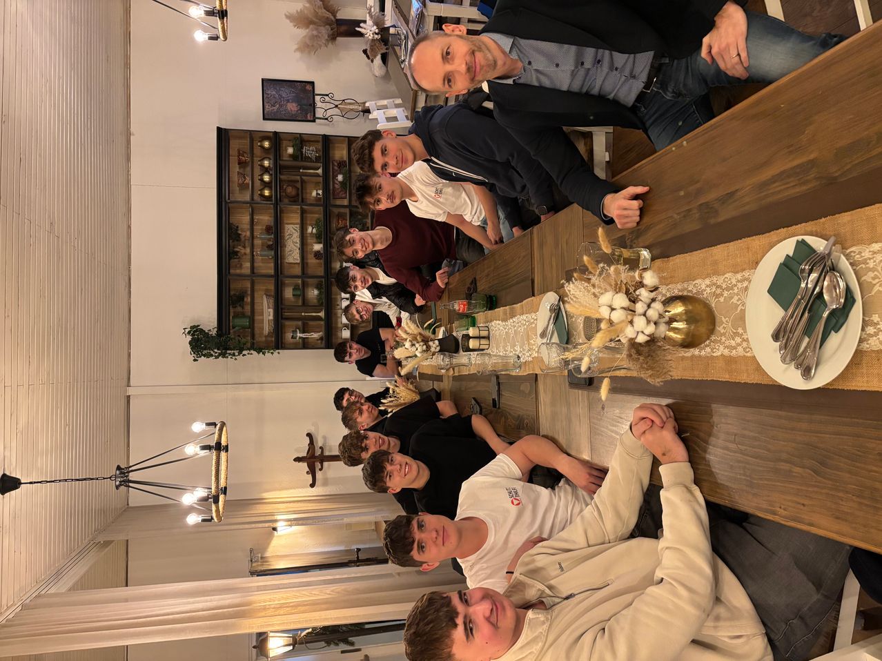 Eine Gruppe junger Männer versammelt sich an einem Tisch in einem Raum mit weißen Wänden. Sie lächeln und scheinen für ein Foto zu posieren.