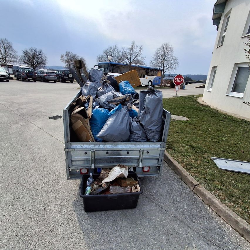 Ein LKW mit einem vollgepackten Laderaum voller Müllsäcke, Kisten und anderen Gegenständen, geparkt auf einer Straße.
