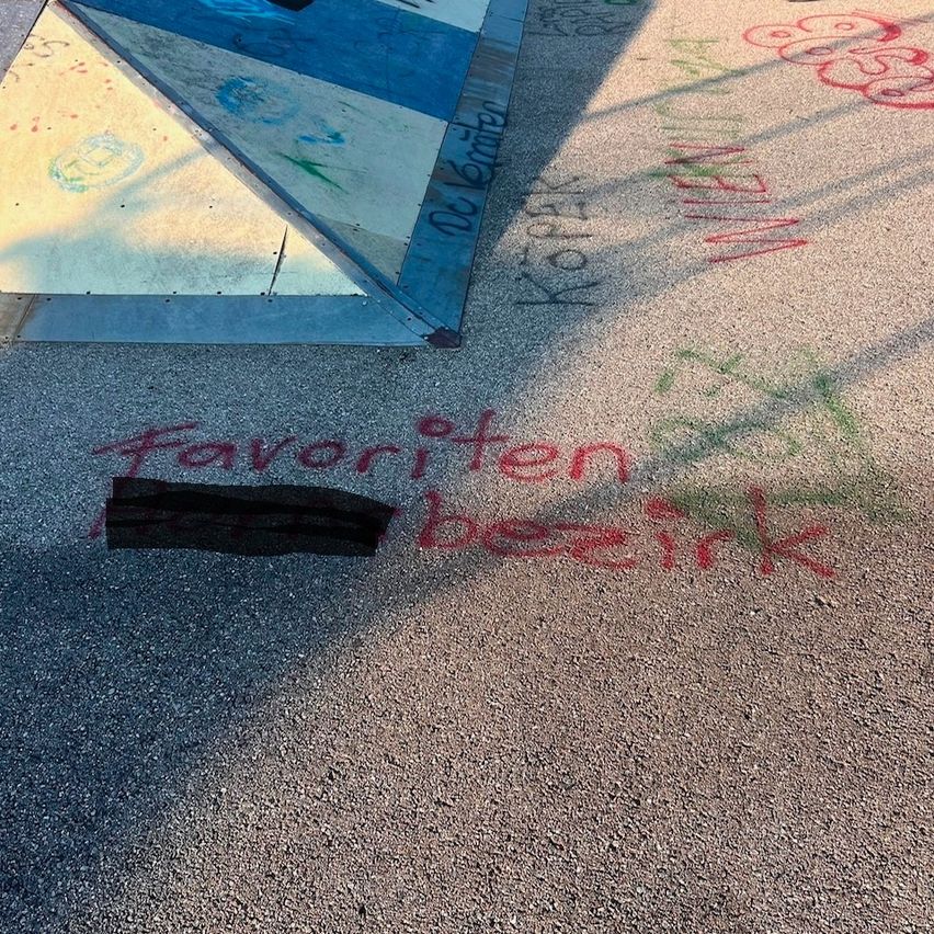 Ein Nahaufnahme von einer Betonoberfläche mit verschiedenen Graffiti, einschließlich 'Favoriten' und 'besink', und einer geometrischen Form mit blauen und weißen Farben.
