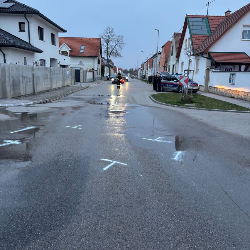 Eine Straße mit weißen Buchstaben darauf und ein Polizeiwagen am Straßenrand geparkt.