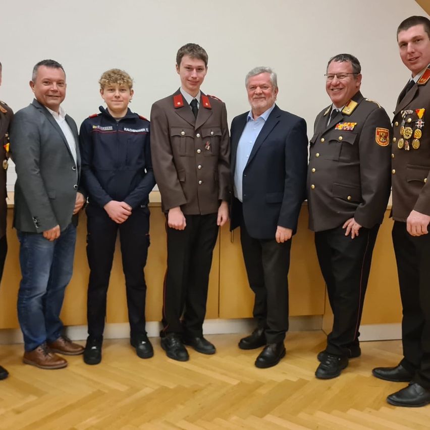 Eine Gruppe von Männern in Uniformen und Anzügen posiert für ein Foto in einer Innenumgebung.