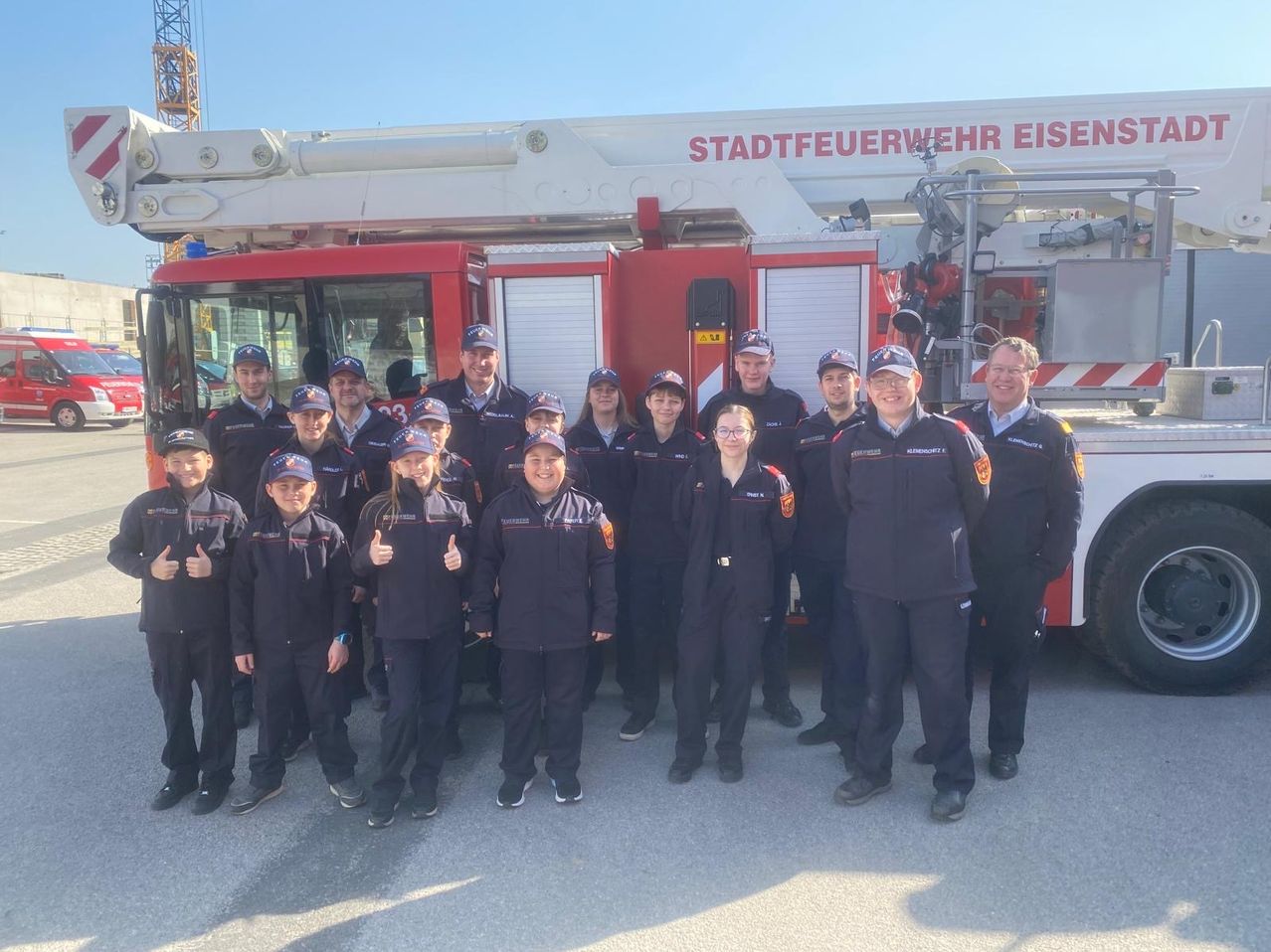 Eine Gruppe von Feuerwehrleuten und Freiwilligen steht vor einem Feuerwehrauto mit der Aufschrift 'Stadtfeuerwehr Eisen'.
