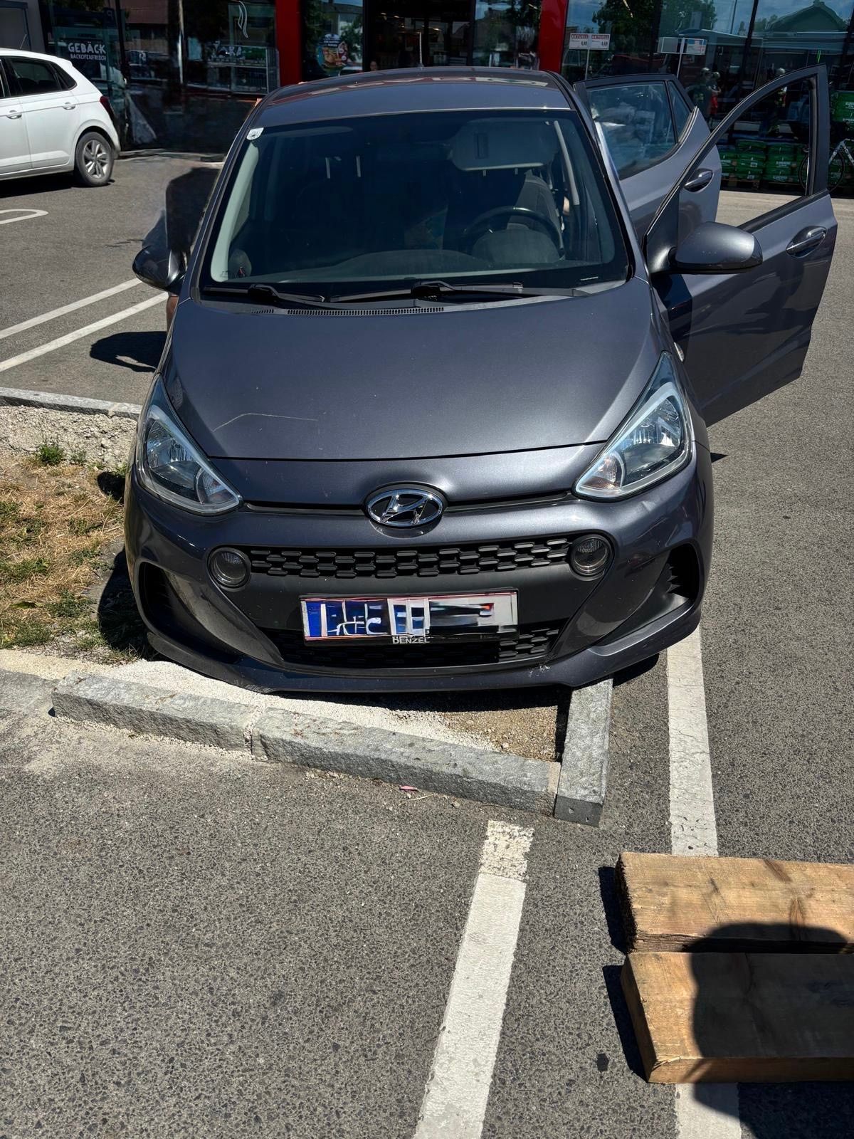 Ein grauer Hyundai mit offener vorderer Tür steht auf einem Parkplatz mit einem Kennzeichen, das 'LC-HI' lautet.