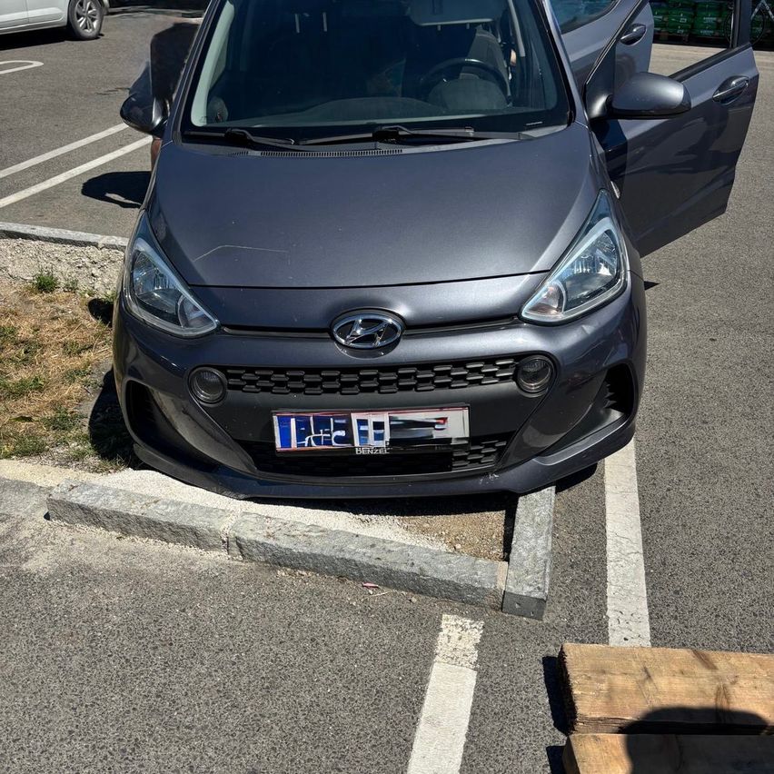 Ein grauer Hyundai mit offener vorderer Tür steht auf einem Parkplatz mit einem Kennzeichen, das 'LC-HI' lautet.