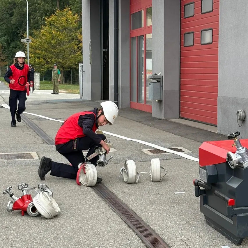 Ein Feuerwehrmann kniet auf dem Boden und repariert einen Hydranten. Ein anderer Feuerwehrmann läuft im Hintergrund.