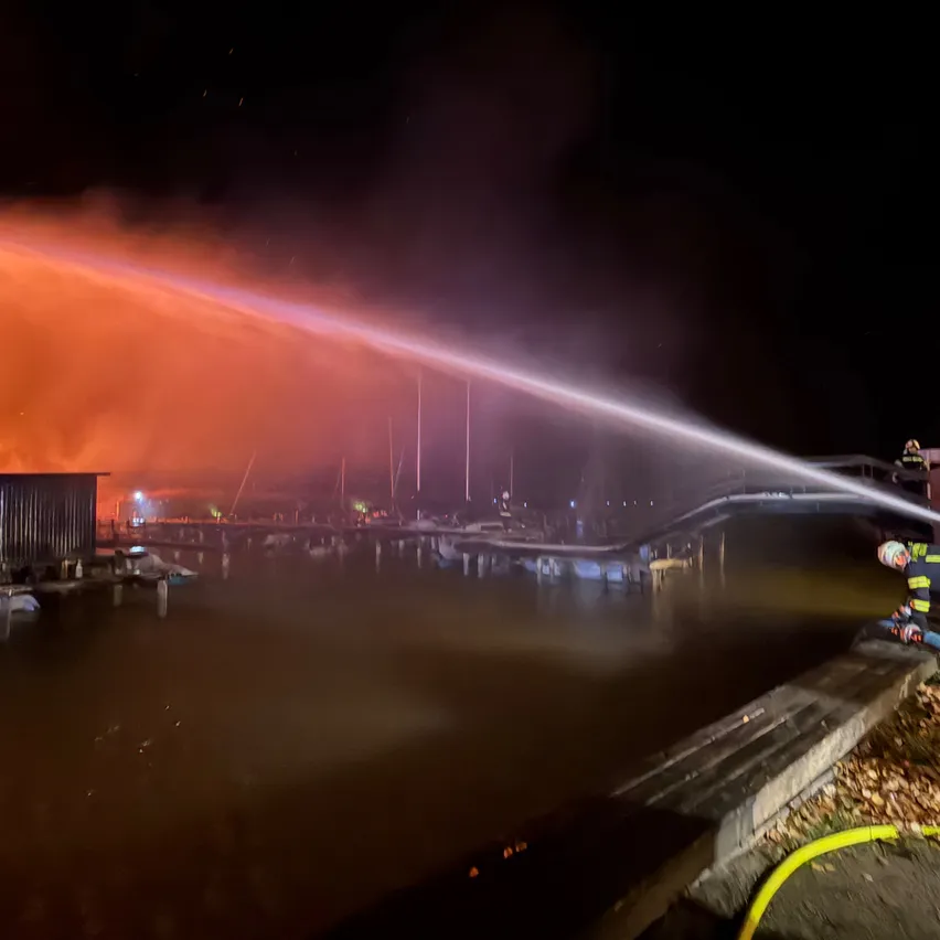 Feuerwehrleute sprühen Wasser aus einem Schlauch, um ein Feuer in der Nacht zu löschen.