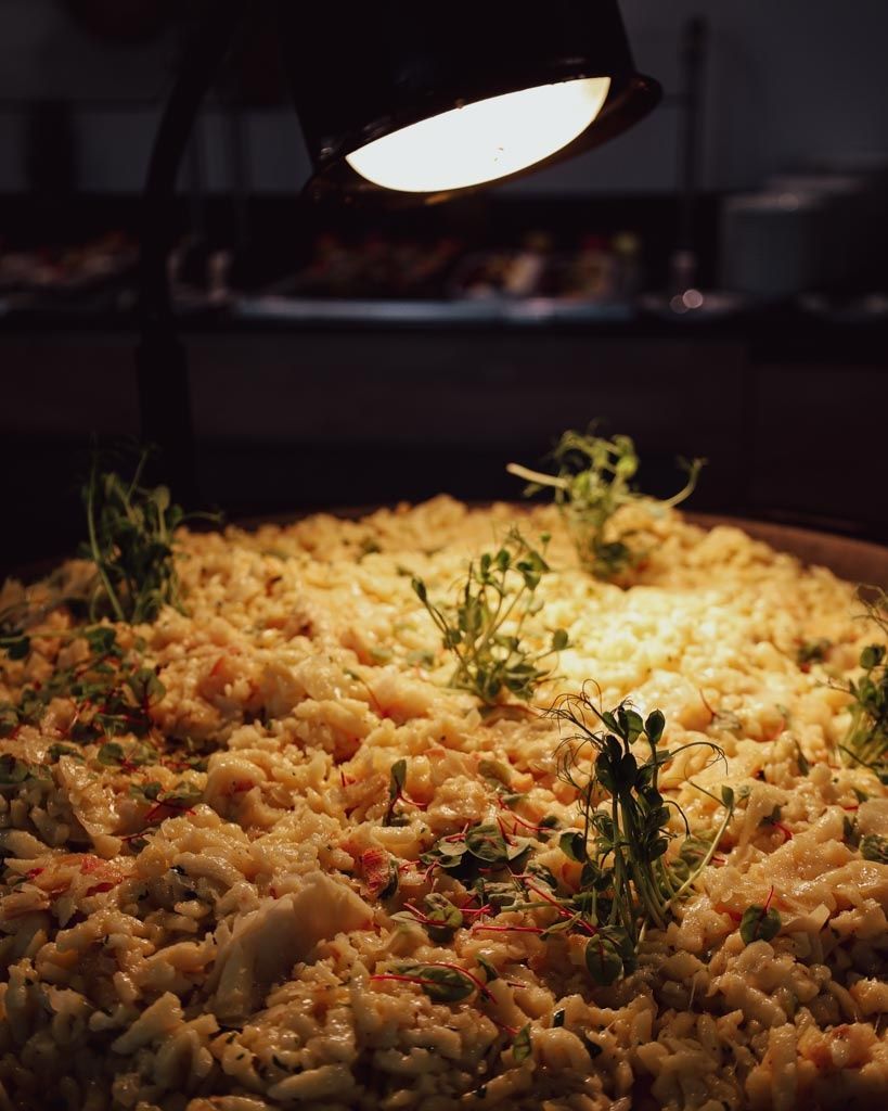 Ein Nahaufnahme eines großen Gerichts, möglicherweise ein Reisgericht, mit grünen Kräutern garniert, beleuchtet von einem hellen Licht.