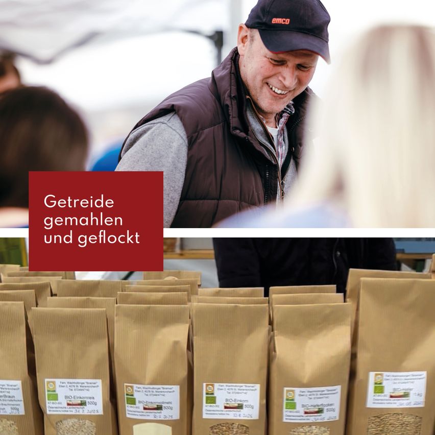 Ein lächelnder Mann in einer braunen Weste schaut eine Frau an, die sich neben einem Stapel brauner Tüten befindet, die mit BIO-Einkorn und BIO-Farro gekennzeichnet sind.