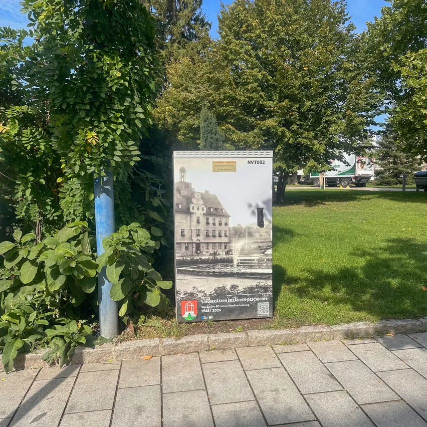 Eine Metallbox mit einem Bild eines Gebäudes steht am Straßenrand.