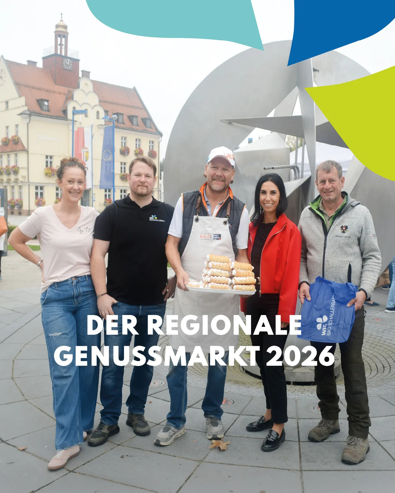 Fünf Personen stehen vor einem Gebäude mit Turm und Uhr. Sie lächeln und posieren für ein Foto.