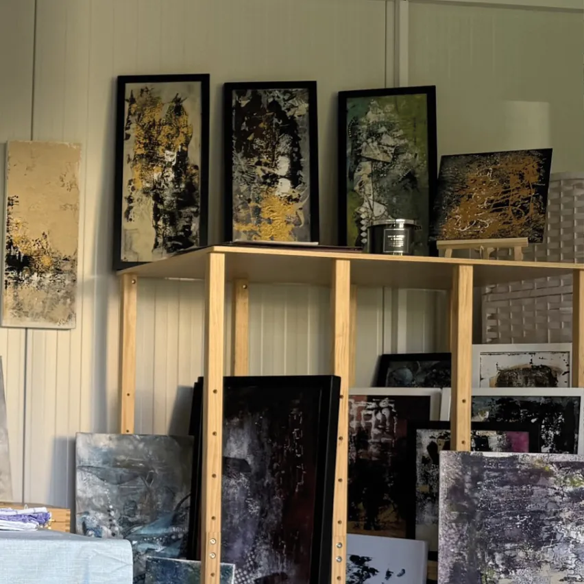 Ein Zimmer mit einem Holzregal, das mit verschiedenen gerahmten Gemälden an der Wand gefüllt ist.
