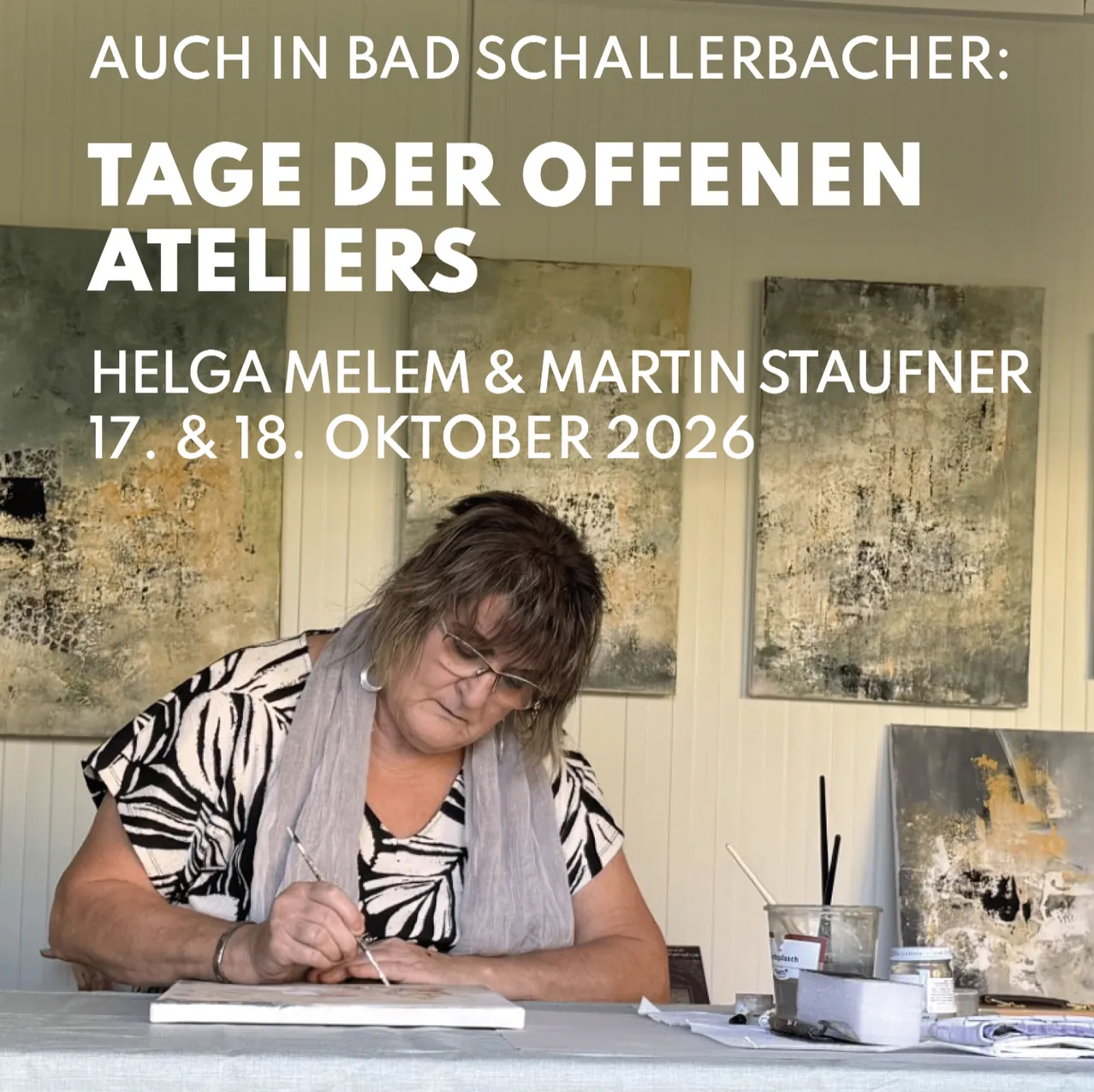 Eine Frau sitzt an einem Tisch und malt ein Bild. Der Tisch hat einen Becher, ein Glas und andere Kunstutensilien. Hinter ihr hängen drei Gemälde an der Wand.