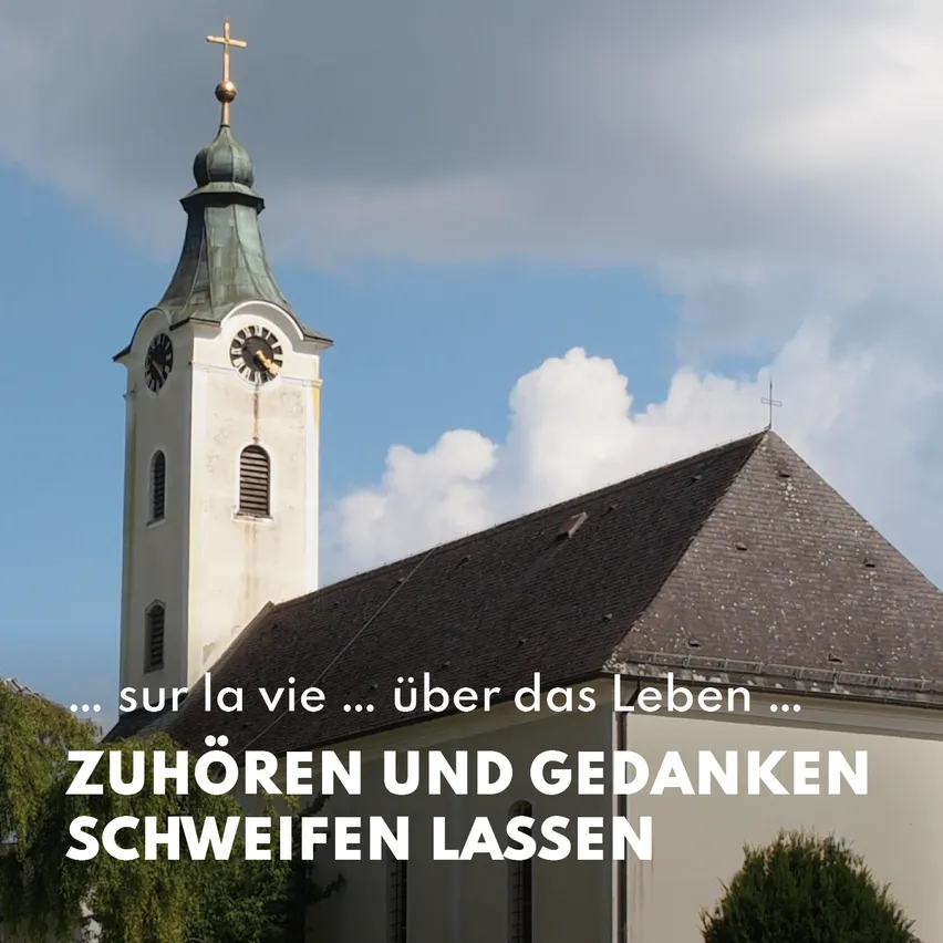 Ein Kirchturm mit einer Uhr und einem Kreuz auf der Spitze. Der Turm ist weiß und hat ein grünes Dach.