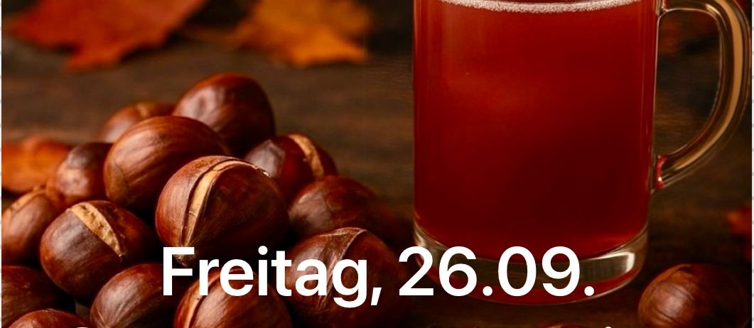 Ein Glasbecher mit rotem Inhalt und einem Griff steht auf einem Holztisch. Er ist von Kastanien und Herbstblättern umgeben. Der Text lautet Freitag, 26.09. Sturm und Kastanien.