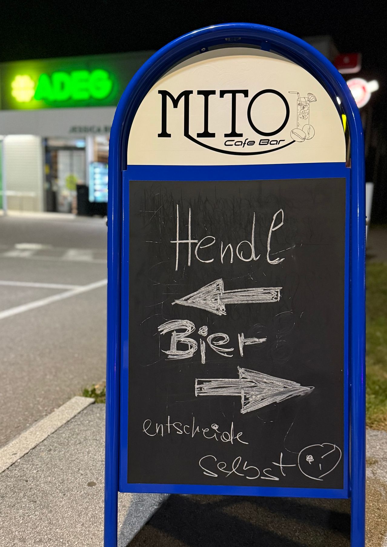 Ein Tafelschild außerhalb eines Café-Bars zeigt an, dass es sowohl Fisch als auch Fleisch serviert. Pfeile zeigen zur Eingangstür.