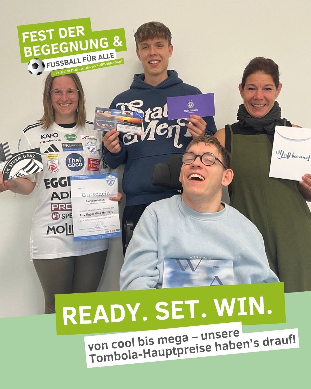 Vier Menschen lächeln und halten Tickets, Urkunden und ein weißes Schild mit den Worten 'Bereit. Set. Gewinnen.' Die Frau links hält ein Fußballtrikot.