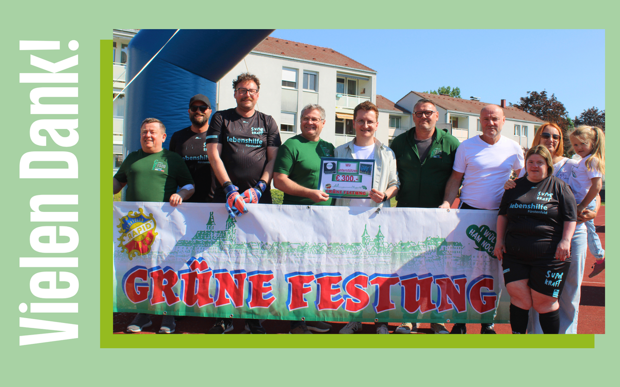 A group of men stands behind a banner, with one holding a certificate. They are dressed in green and white jerseys. Behind them is a blue inflatable and buildings.