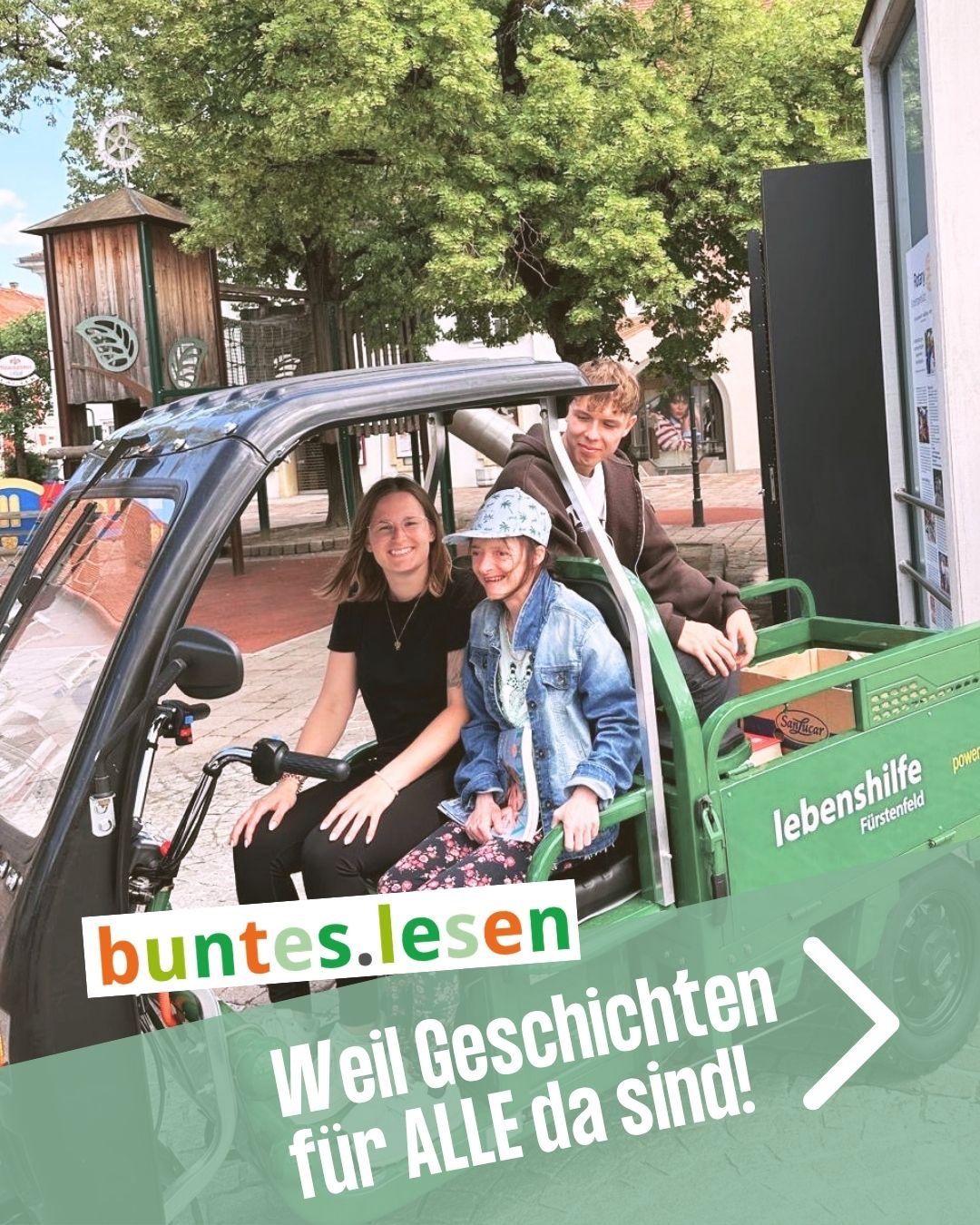 Drei Personen sitzen in einem grünen Fahrzeug mit der Textüberlagerung 'buntes.lesen' und 'Weil Geschichten sind!' Eine Frau lächelt, während die anderen nach vorne schauen. Hinter ihnen sind ein Spielplatz und ein Gebäude zu sehen.