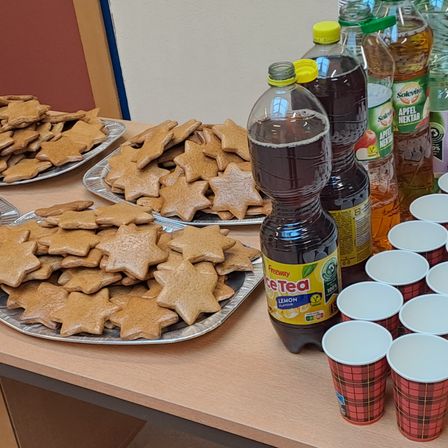 Ein Tisch mit Tabletts voller Lebkuchenplätzchen, einer Flasche Eistee und Plastikbechern.