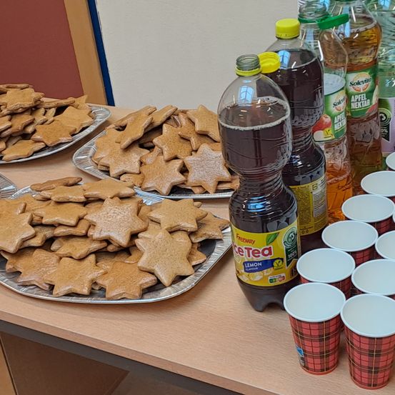 Ein Tisch mit Tabletts voller Lebkuchenplätzchen, einer Flasche Eistee und Plastikbechern.