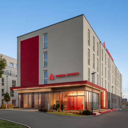 Das Äußere eines modernen Hotels mit einer roten Fassade und roten Buchstaben, die 'AMEDIA EXPRESS' auf der Seite stehen.