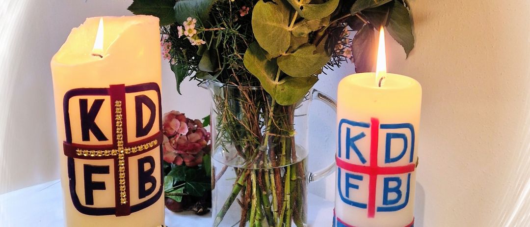 Zwei Kerzen, eine mit der Nummer 25 und die andere mit 35, stehen neben einem Blumenstrauß auf einem weißen Tisch.