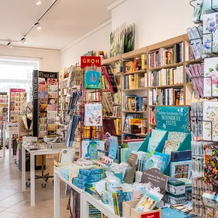 Ein Buchladen mit vielen Büchern und Artikeln zur Schau gestellt. Der Laden hat eine große Auswahl an Büchern in Regalen, Geschenkboxen und anderen Artikeln. Der Laden ist gut beleuchtet mit Lampen an der Decke.