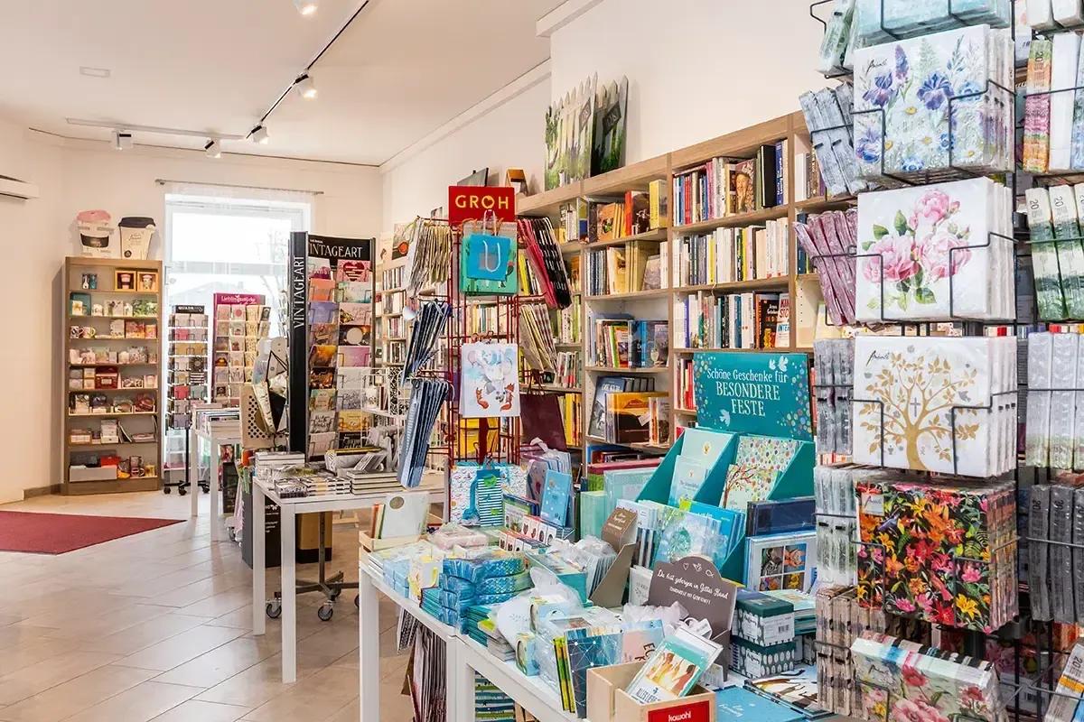 Ein Buchladen mit vielen Büchern und Artikeln zur Schau gestellt. Der Laden hat eine große Auswahl an Büchern in Regalen, Geschenkboxen und anderen Artikeln. Der Laden ist gut beleuchtet mit Lampen an der Decke.