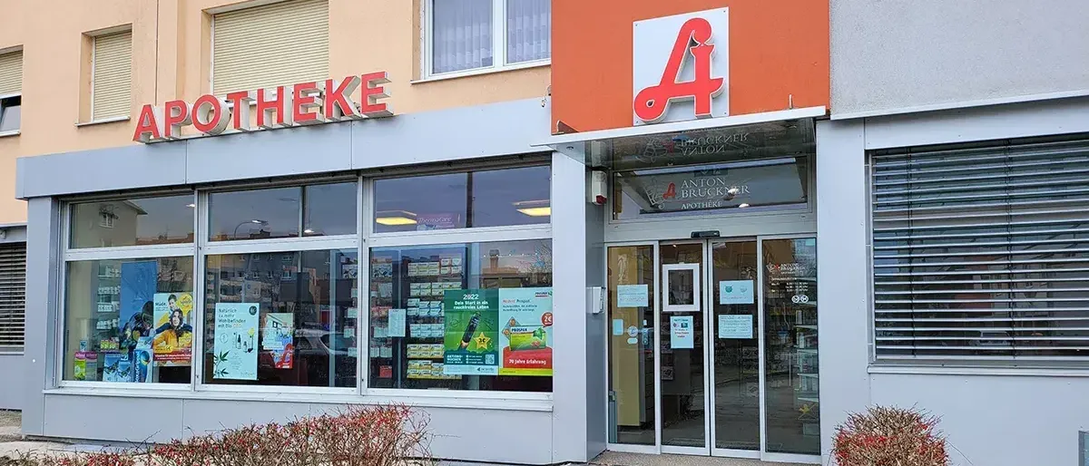 Eine Apotheke mit dem Namen Apotheke, mit Glasfenstern und einem Eingang mit dem Buchstaben A oben.