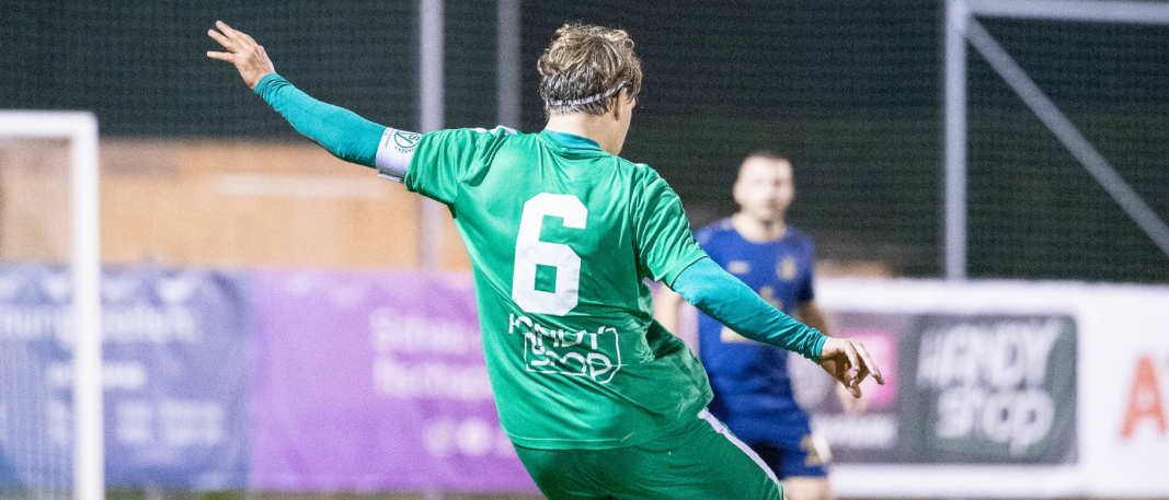 Fußballspieler in grüner Uniform tritt den Ball auf einem Fußballfeld. Das Event findet am Dienstag, 18. Februar, um 20:00 bei KR Traiskirchen statt.