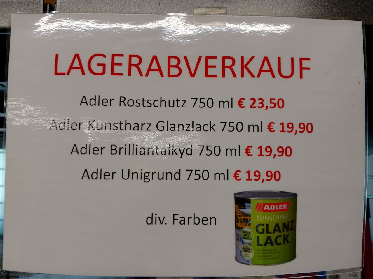 Das Bild zeigt ein Schild für einen Ausverkauf bei Adler. Verfügbar sind Adler Rostschutz für 750 ml zu 23,50 Euro, Adler Kunstharz Glanzlack für 750 ml zu 19,90 Euro, Adler Brilliant Akyd für 750 ml zu 19,90 Euro und Adler Unigrund für 750 ml zu 19,90 Euro. Der Preis ist unterschiedlich. Eine Adler Dose Kunstharz Glanzlack ist abgebildet.