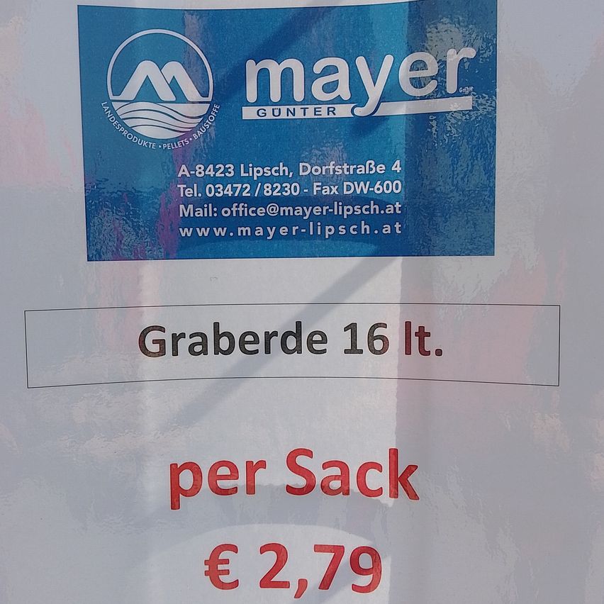 Ein Schild von Mayer mit Kontaktdaten und Preisinformationen für Graberde 16 Lt. zu 2,79 Euro pro Sack.
