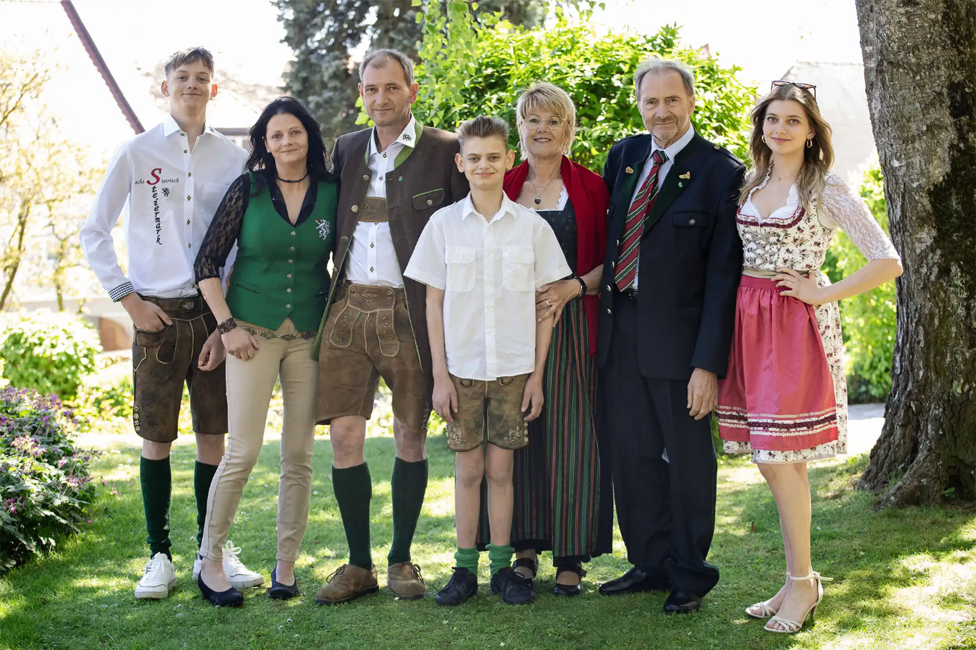 Eine sechsköpfige Familie, gekleidet in traditioneller deutscher Kleidung, posiert für ein Foto auf einem Rasen.