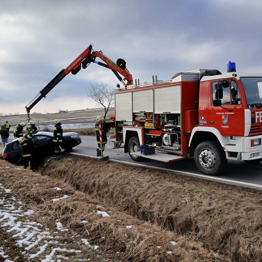 Firefighters are rescuing a person from a wrecked car with the help of a crane on the roadside.