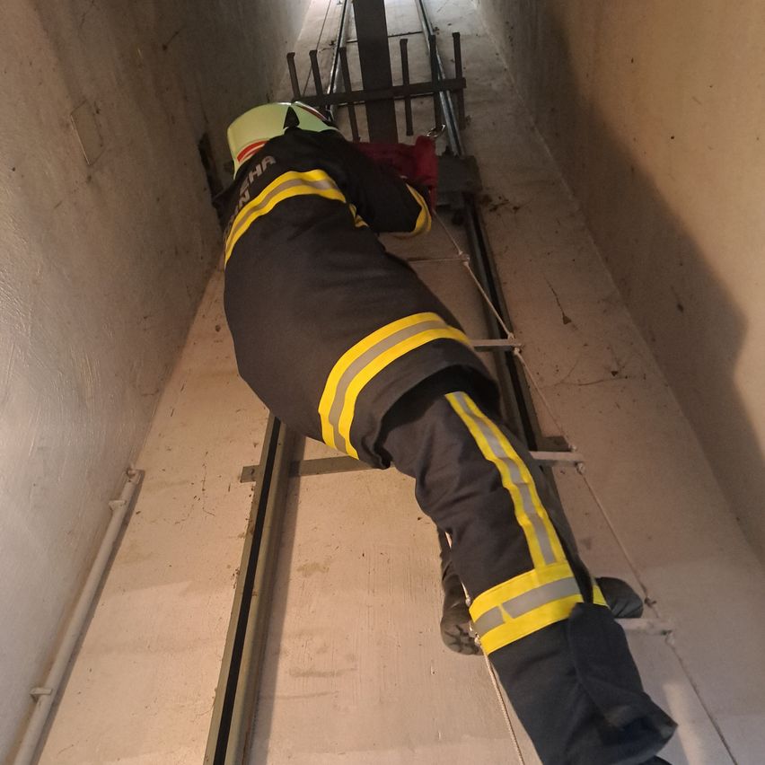 Ein Feuerwehrmann in voller Schutzkleidung liegt auf einer Trage in einem Tunnel, möglicherweise während einer Übung.