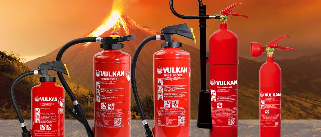 Drei rote Vulkan-Feuerlöscher sind vor dem Hintergrund einer Vulkaneruption dargestellt. Jeder Löscher hat einen schwarzen Schlauch und einen roten Auslöser. Die Etiketten enthalten Sicherheitshinweise.