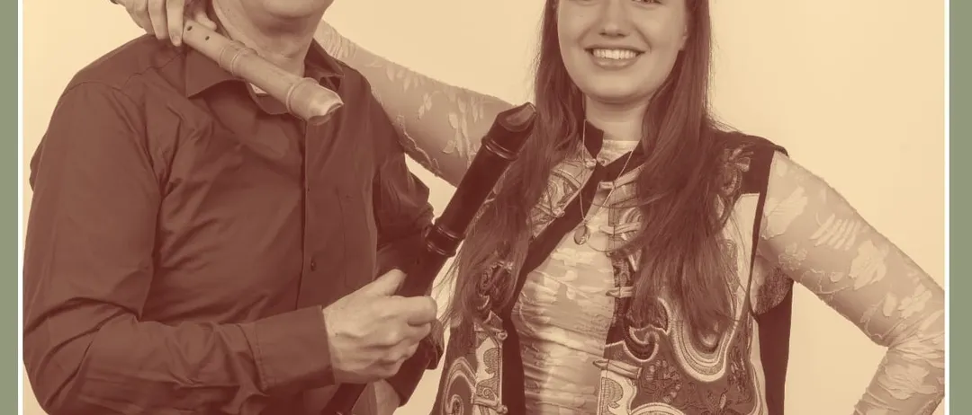 Ein Schwarz-Weiß-Foto von zwei Musikern, einem Mann und einer Frau, die zusammenstehen und lächeln. Der Mann hält eine Flöte und die Frau eine Blockflöte. Unten ist das Datum 12.09.26 zu sehen.