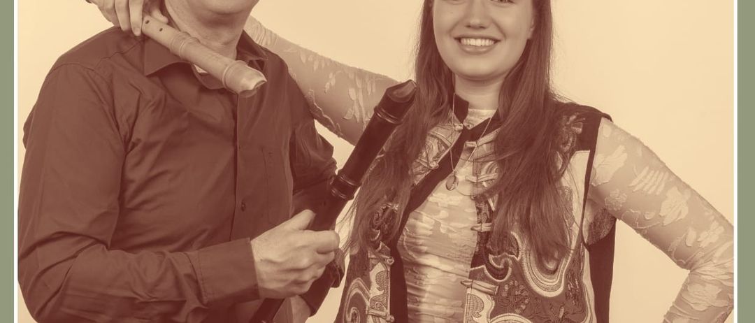Ein Schwarz-Weiß-Foto von zwei Musikern, einem Mann und einer Frau, die zusammenstehen und lächeln. Der Mann hält eine Flöte und die Frau eine Blockflöte. Unten ist das Datum 12.09.26 zu sehen.