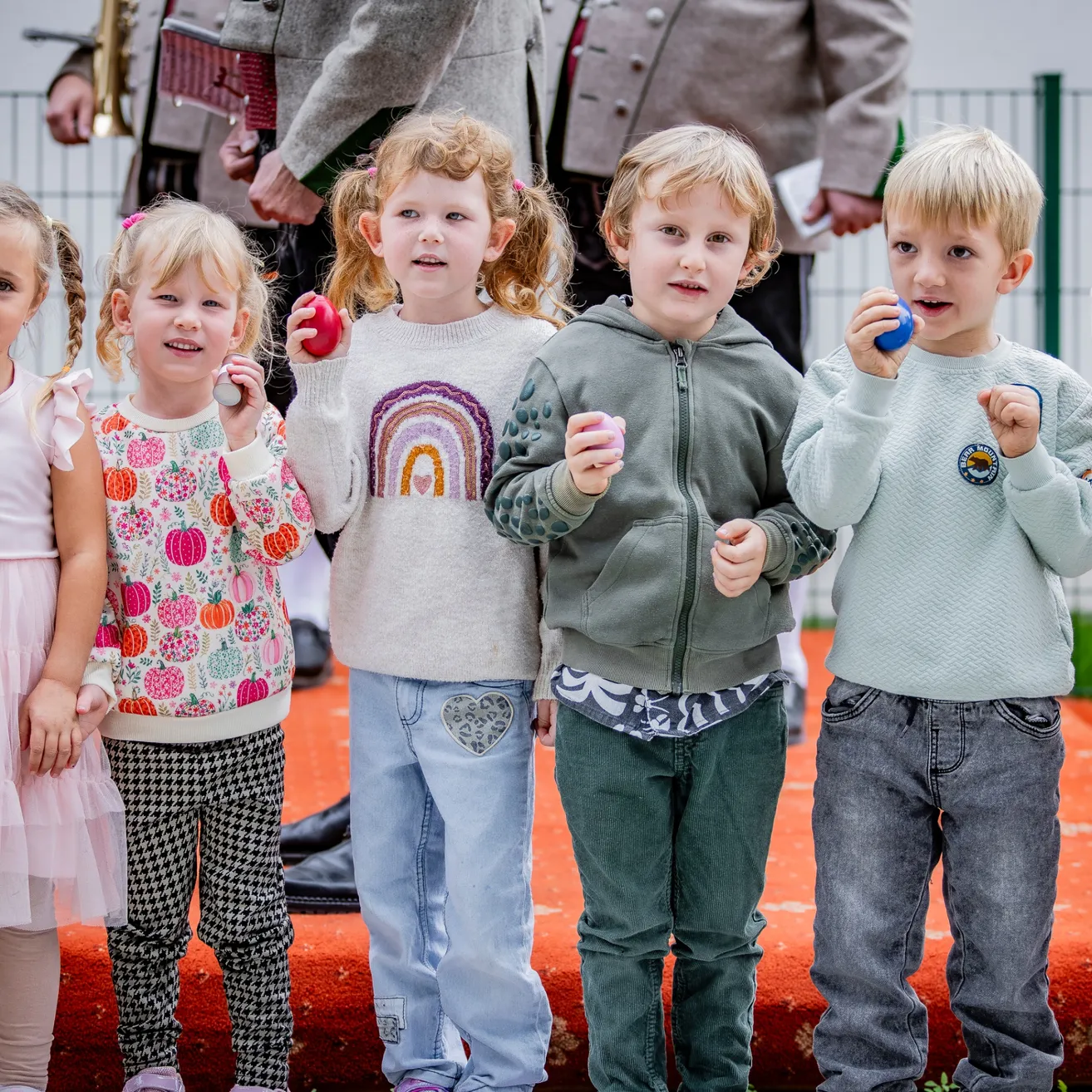 Eine Gruppe von Kindern steht zusammen und hält bunte Eier. Sie lächeln und schauen in die Kamera.