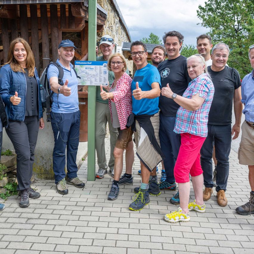 Eine Gruppe von Erwachsenen lächelt für ein Foto vor einem Gebäude mit Bäumen im Hintergrund.