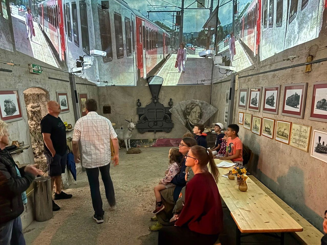 Museumsbesucher sehen Projektionen von Zügen und historische Bilder in einem Ausstellungsraum
