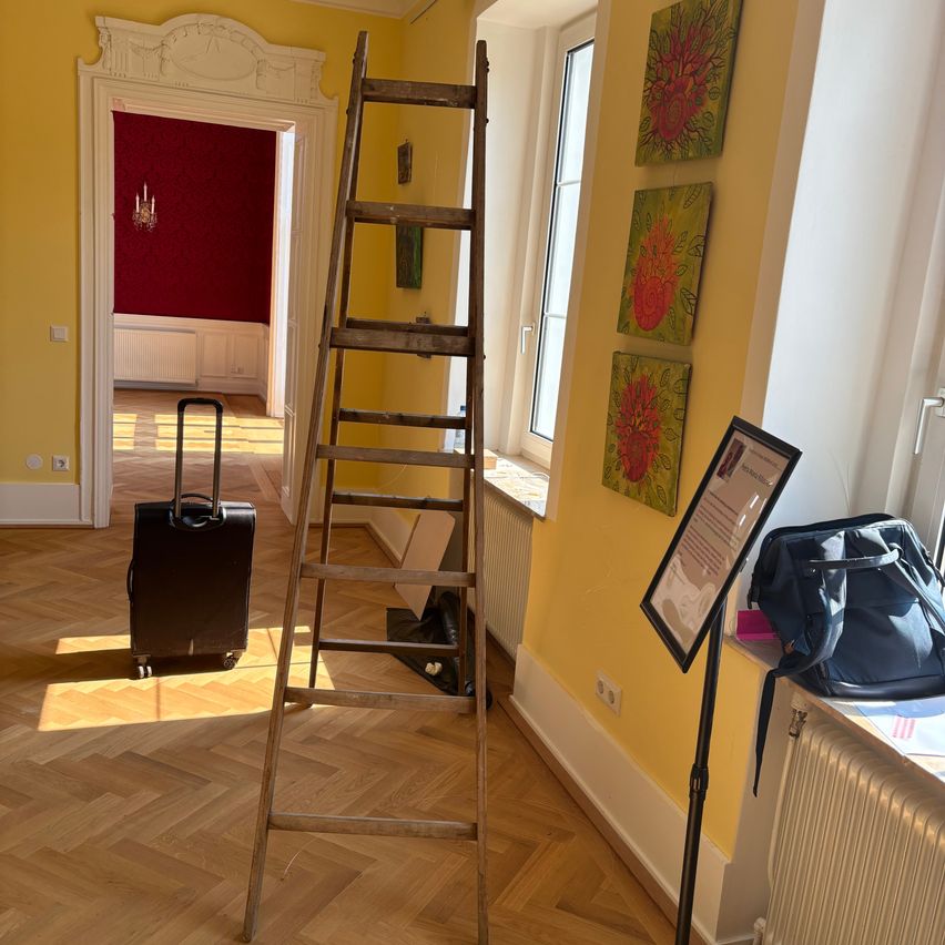 Leiter mit Koffer und Kunst im gelben Raum in Wien