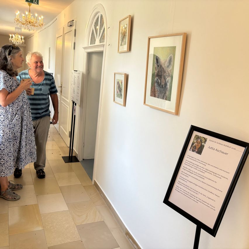 Jutta Aschauer im Schloss Münchhof mit Bildern von Tieren, ein Paar im Gespräch