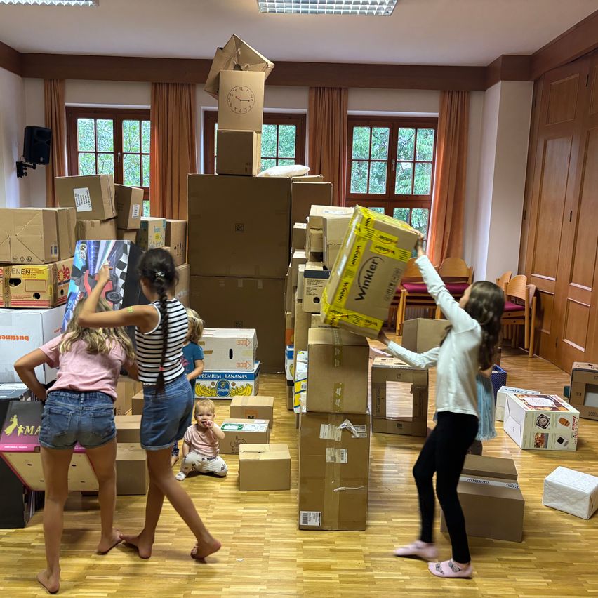 Kinder bauen Türme aus Kartons in einem Raum in Österreich.