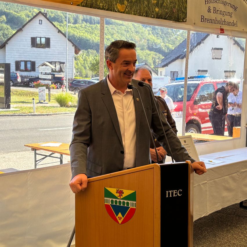 Bürgermeister spricht am Rednerpult mit Gemeindewappen in St. Johann im Pongau