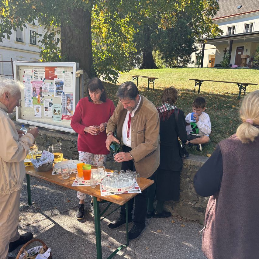 Männer mit Tracht und Frauen bei einem Getränkeausschank im Freien
